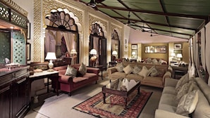 A spacious living room with a high ceiling, ornate wall decorations, and multiple seating areas. - Rohet Garh (Rohat)