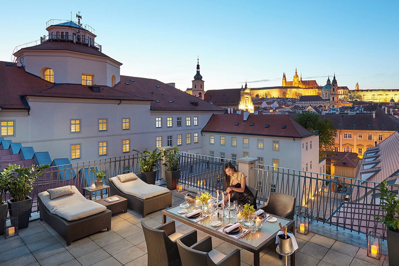 A rooftop terrace with outdoor seating and a view of historic buildings.