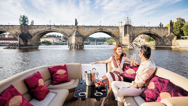 A boat with a table and cushions, a bridge in the background, and a river. - Mandarin Oriental, Prague (Prague)