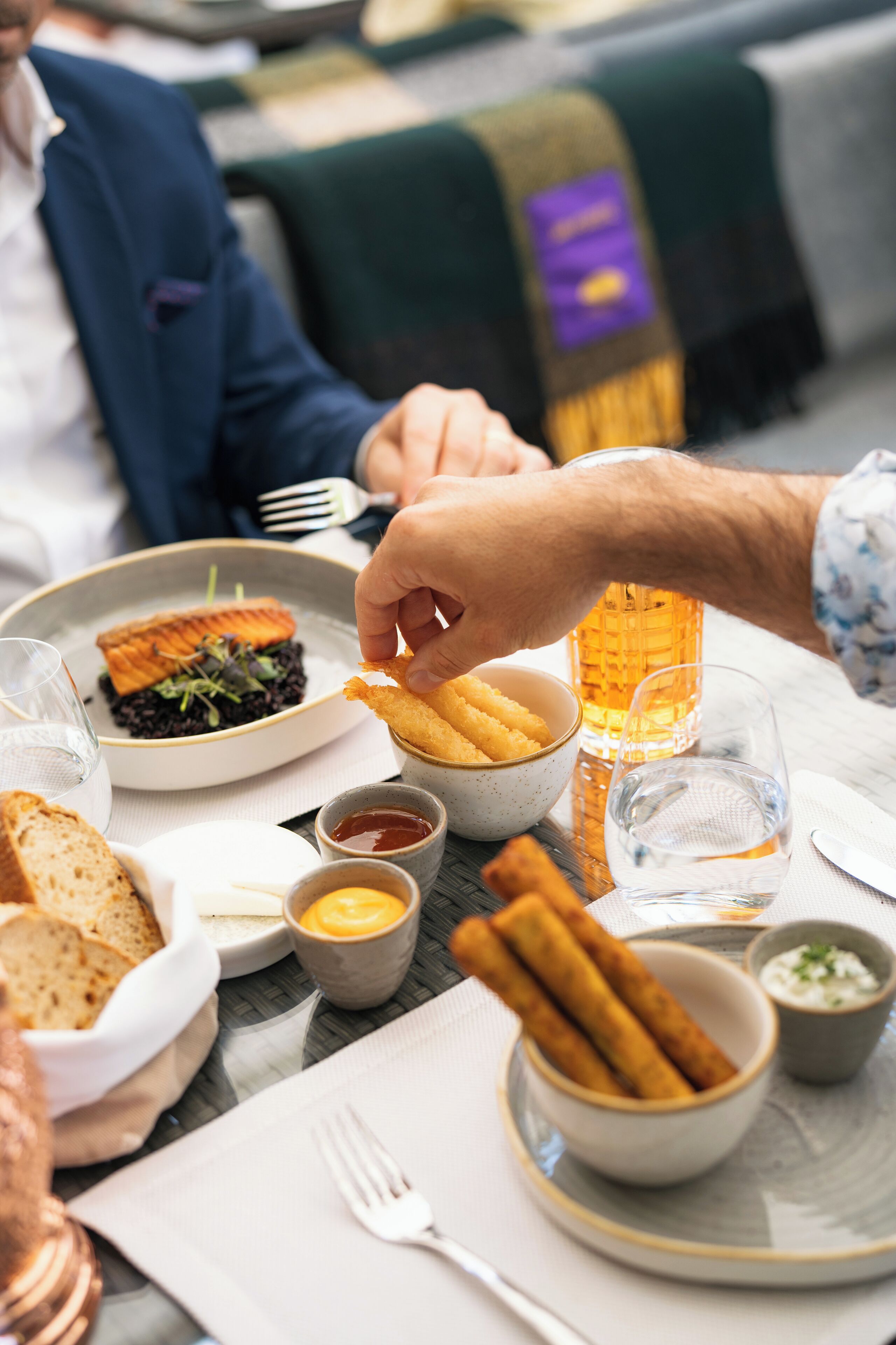 Ein Esstisch mit verschiedenen Speisen, darunter eine Schüssel Pommes, ein Glas Bier und ein Teller Essen.