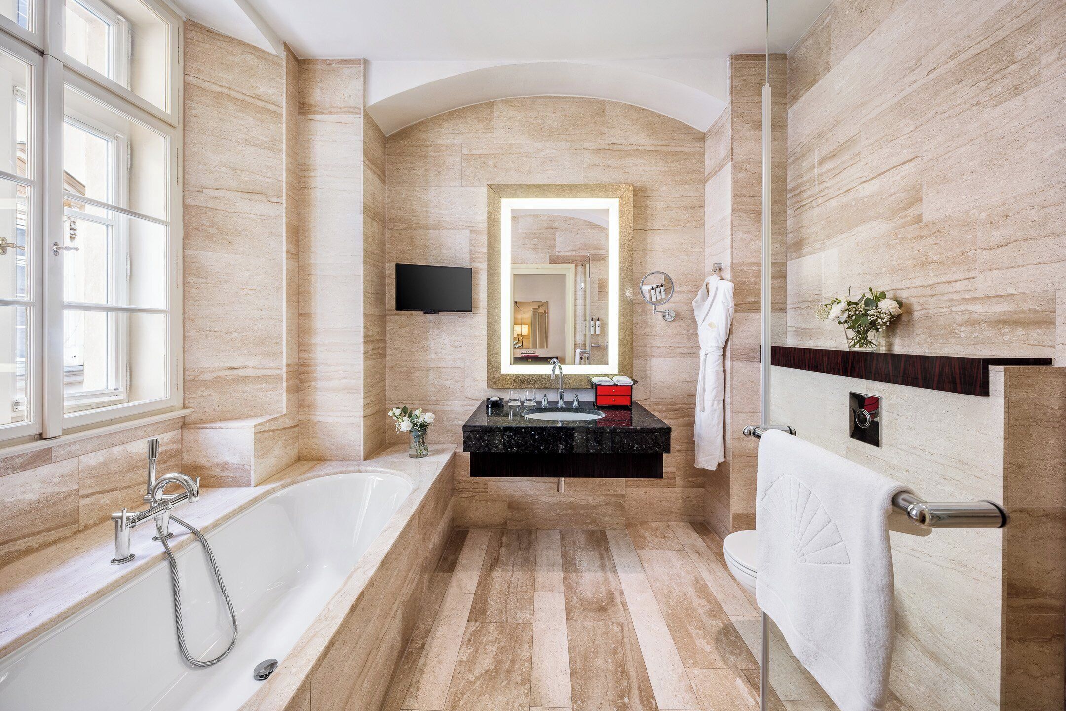 A modern bathroom with a large bathtub, a vanity with a mirror, and a shower area.