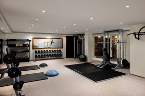 A home gym with weightlifting equipment, dumbbells, and exercise mats.