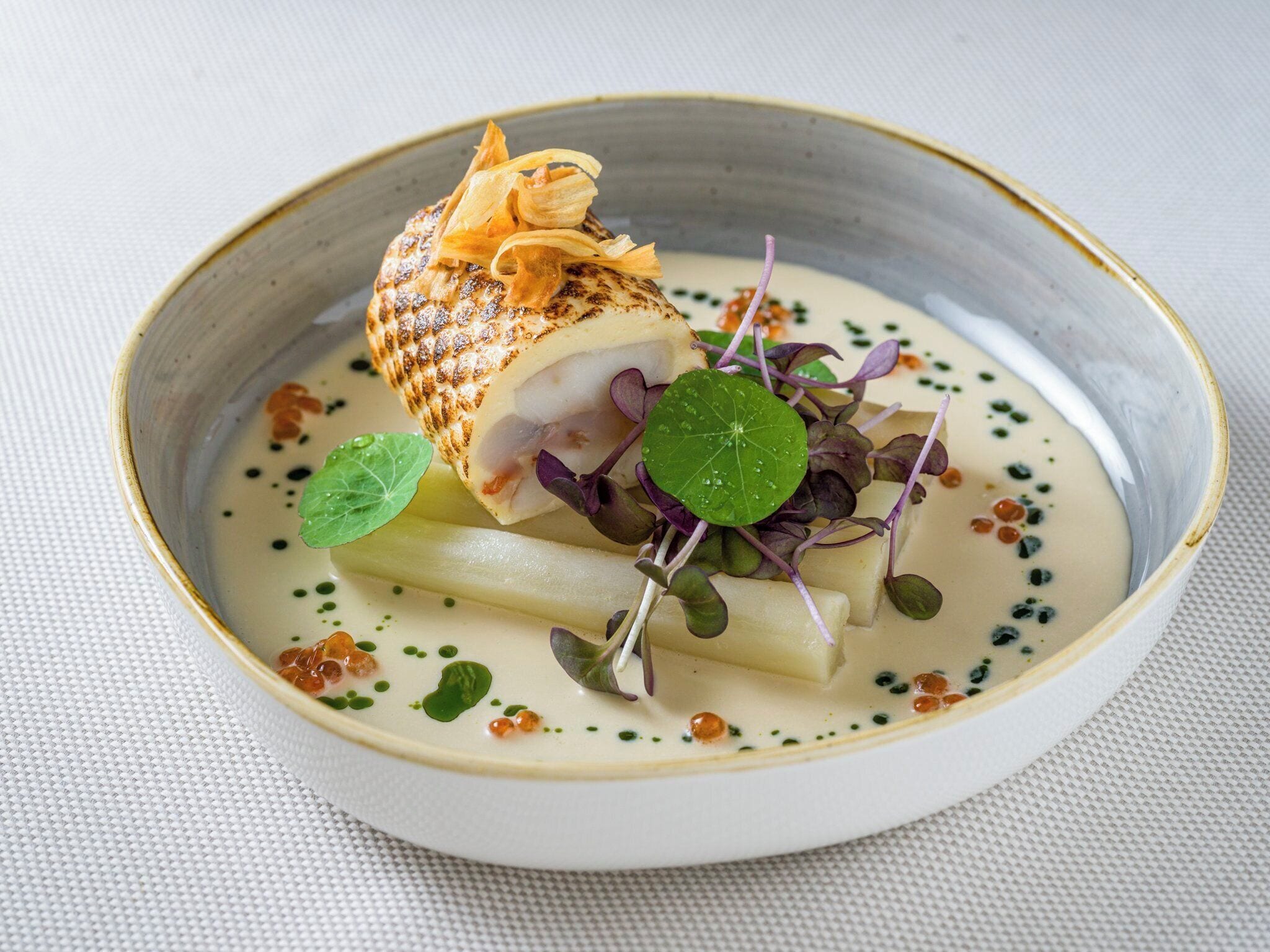 Prato com frutos do mar, vegetais e molho cremoso em uma tigela de cerâmica.
