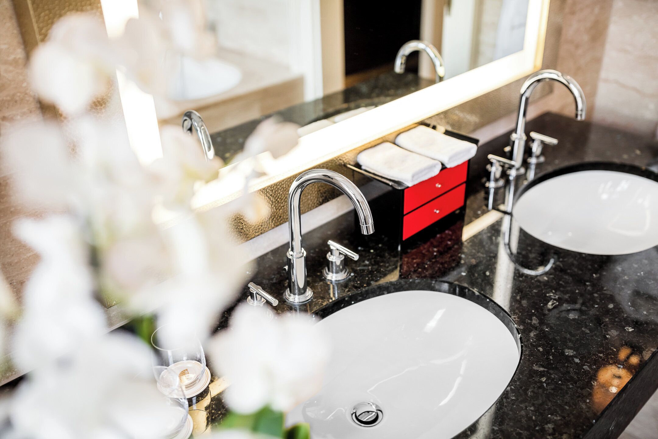 A bathroom with two sinks, a mirror, and a red storage box.