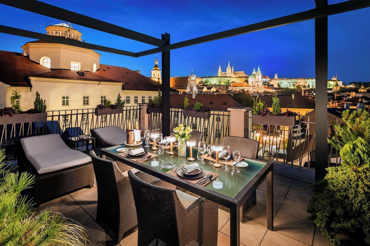 An outdoor dining area with wicker furniture and a view of historic buildings in the background.