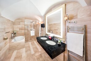 Une salle de bain moderne avec deux lavabos, un grand miroir, une douche en verre et un porte-serviettes.