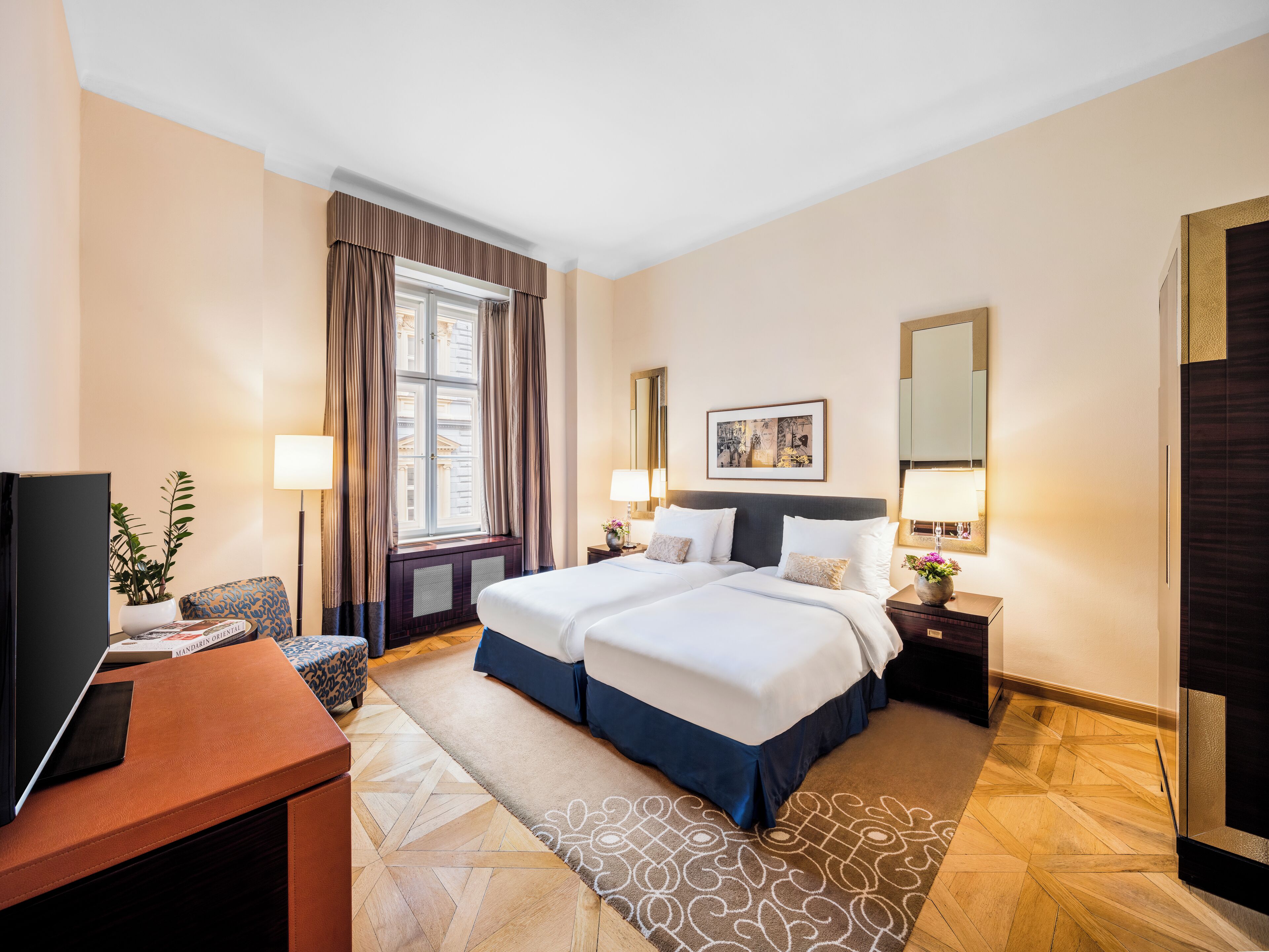 Une chambre d’hôtel avec un lit double, un bureau avec un ordinateur, une chaise, une fenêtre avec des rideaux, une table de chevet avec une lampe et un tableau encadré au mur.