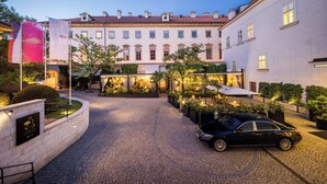 A courtyard with cobblestone paving, a black car, and a building with a red-tiled roof. - Mandarin Oriental, Prague (Prague)