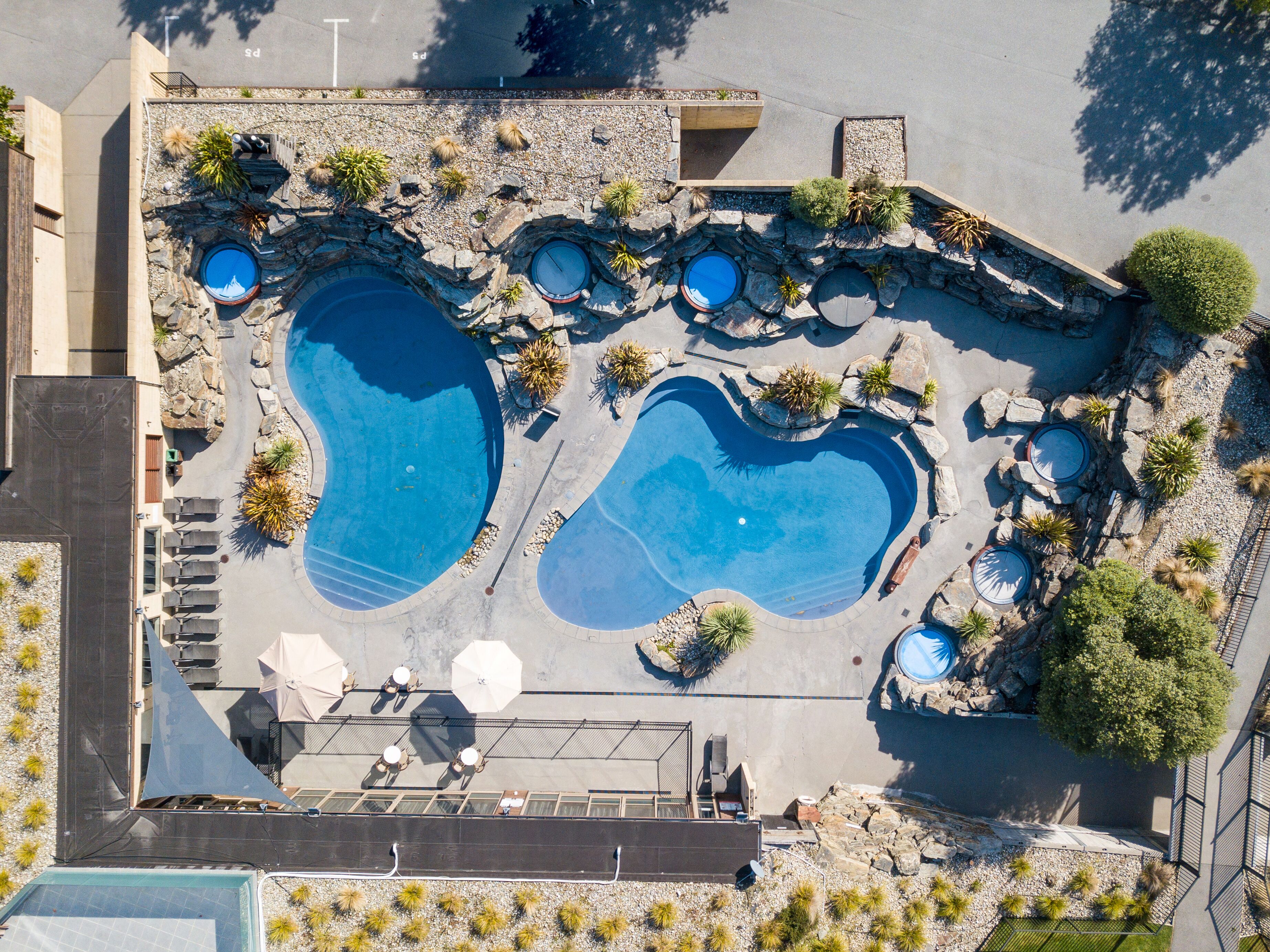 An aerial view of a resort with multiple swimming pools, sun loungers, and a covered seating area.