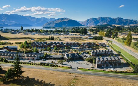 A residential area with multiple apartment buildings, a road, and mountains in the background.