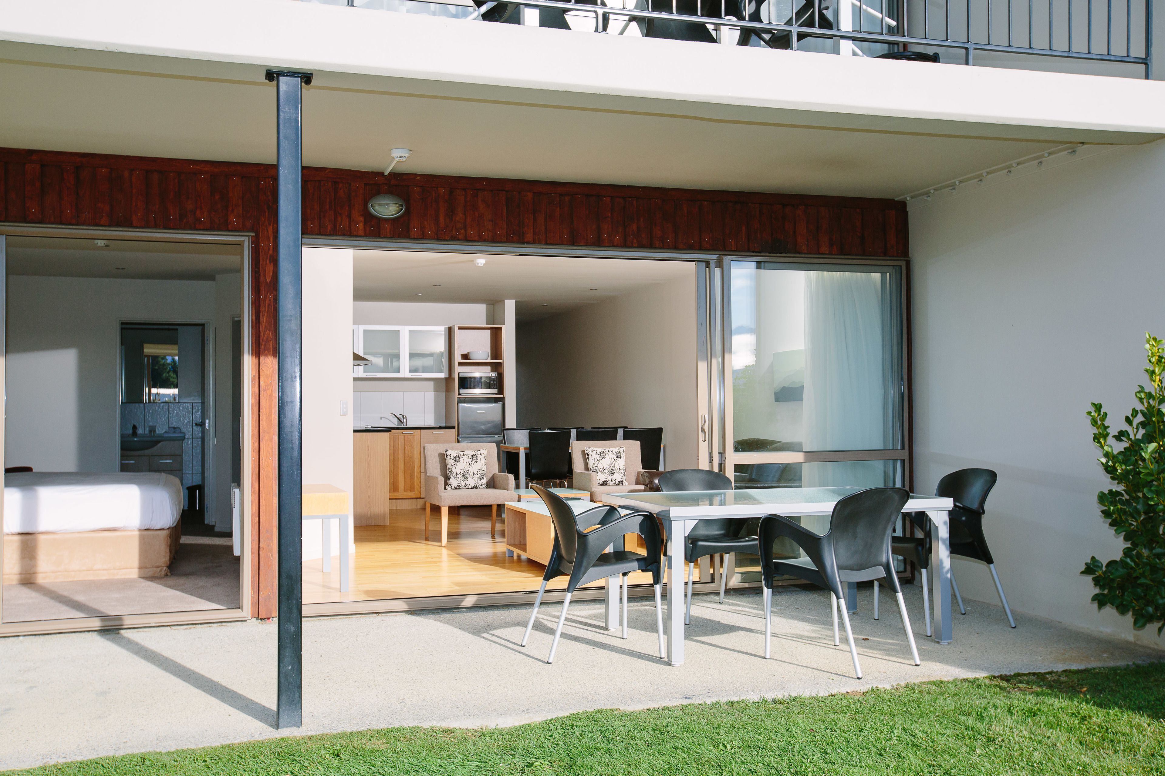 A modern apartment with a glass door entrance leading to a dining area with a table and chairs.