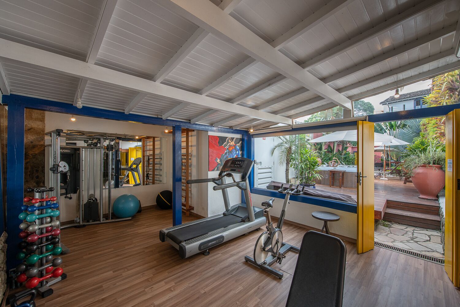 Uma academia com equipamentos de cardio, aparelhos de musculação e espelhos.