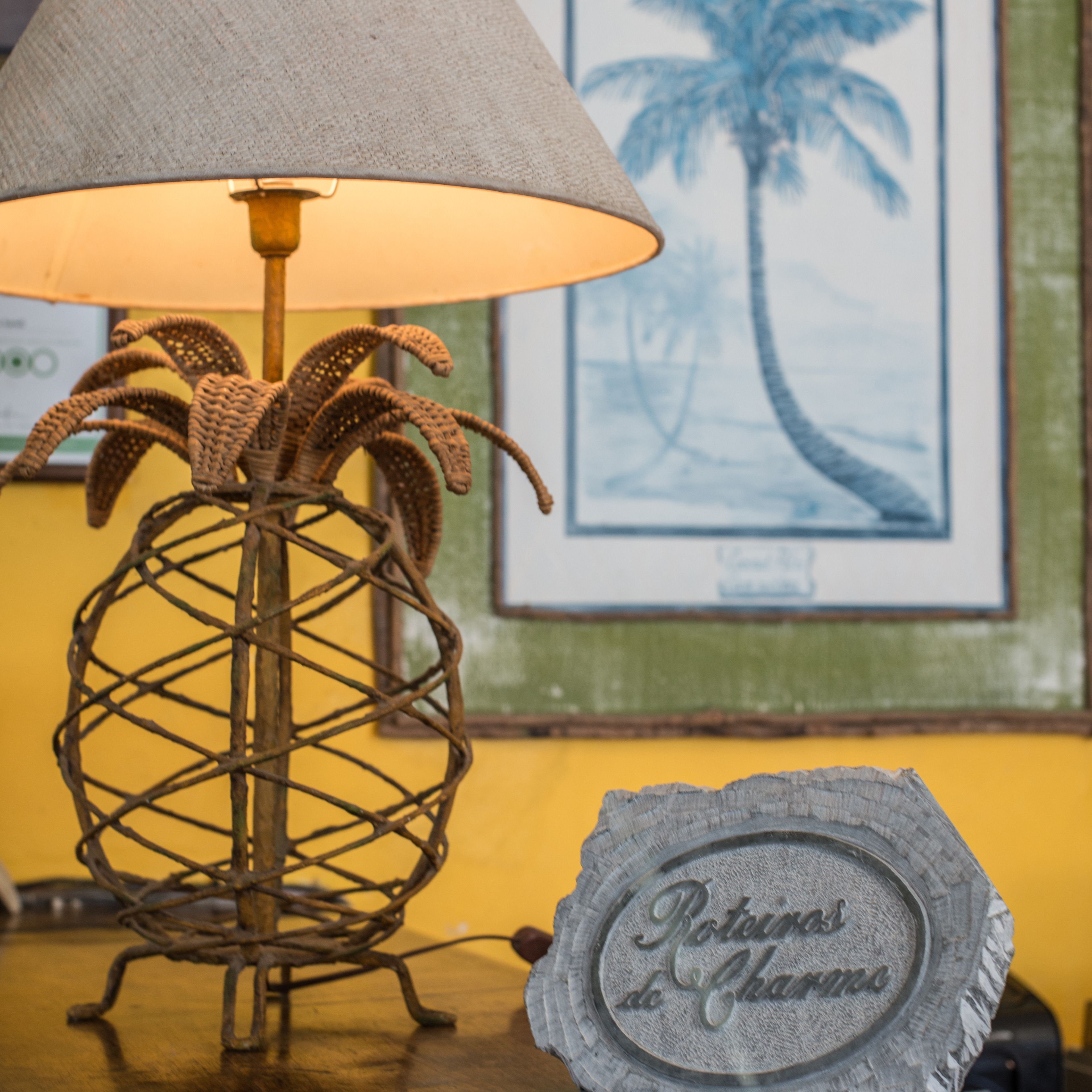 A lamp with a textured shade, a woven plant holder, and a wooden plaque with text.