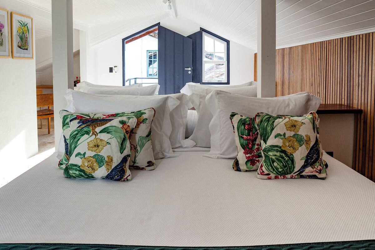 A bedroom with a bed, pillows, and a view of the outside.