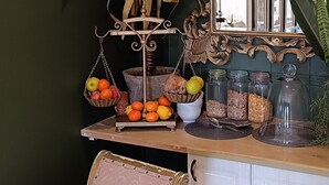 Un coin repas avec une table dressée pour deux personnes, une plante décorative et un miroir doté d’un cadre orné.
