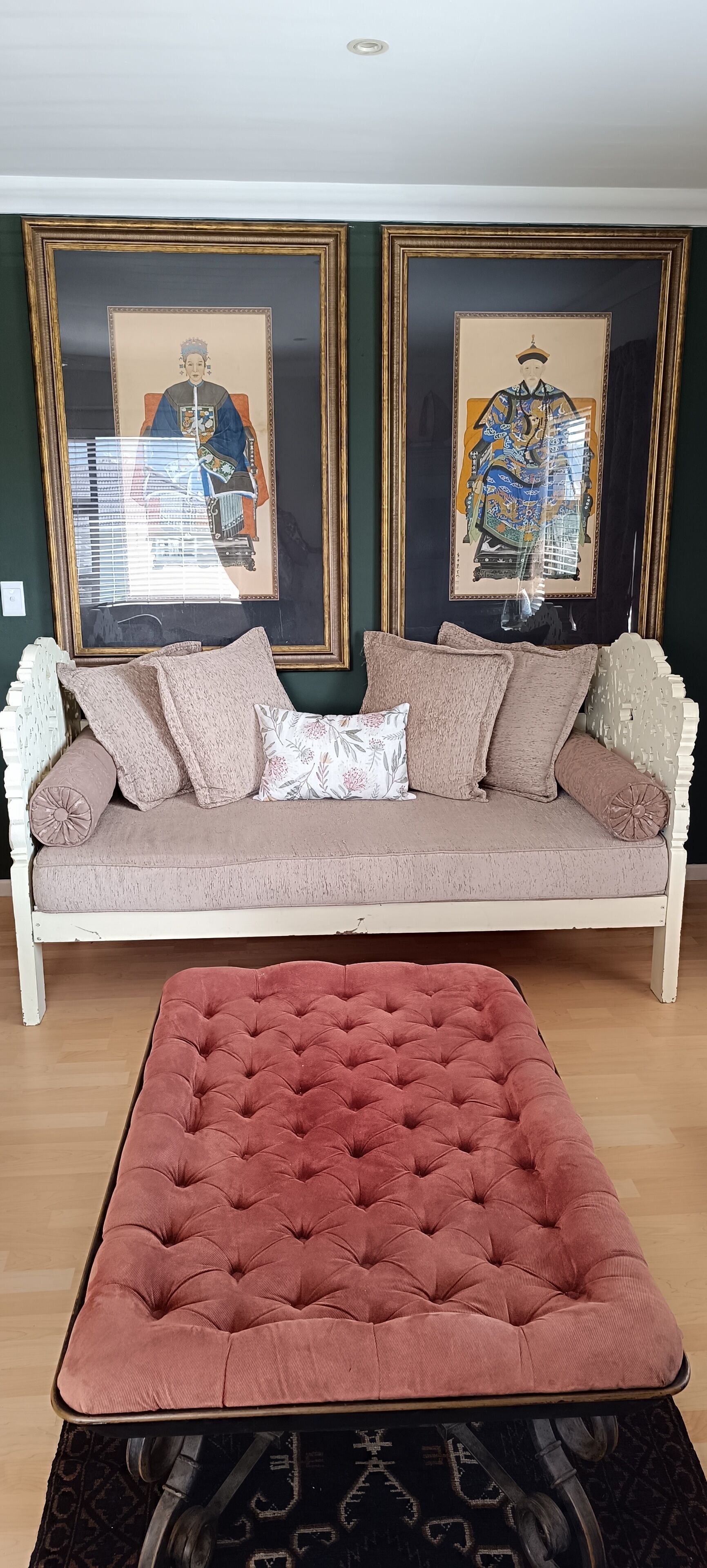 A living room with a white sofa, a pink ottoman, and two framed artworks on the wall.