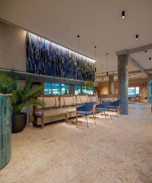 A spacious lobby with a seating area, a decorative wall, and a large pillar. - Hotel Agua del Desierto (Calama)
