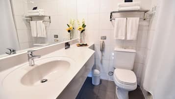 A modern bathroom with a large sink, toilet, and towel rack.