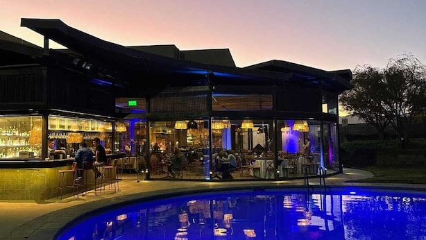 An outdoor bar area with a pool, seating, and a modern architectural design. - Hotel Agua del Desierto (Calama)