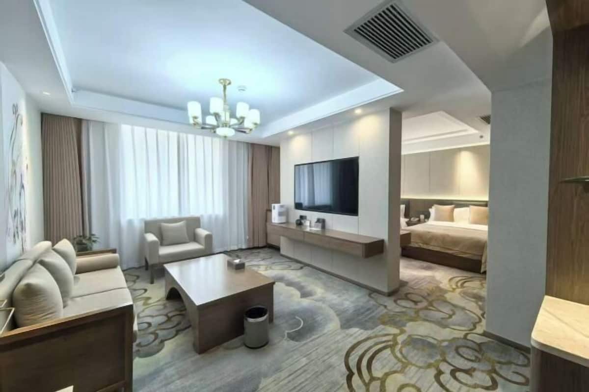 A modern hotel room with a sofa, a coffee table, a TV, and a bed.