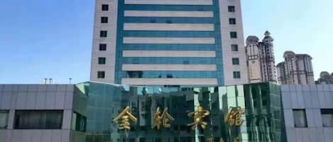 A modern building with a reflective glass facade and a prominent sign in gold characters.