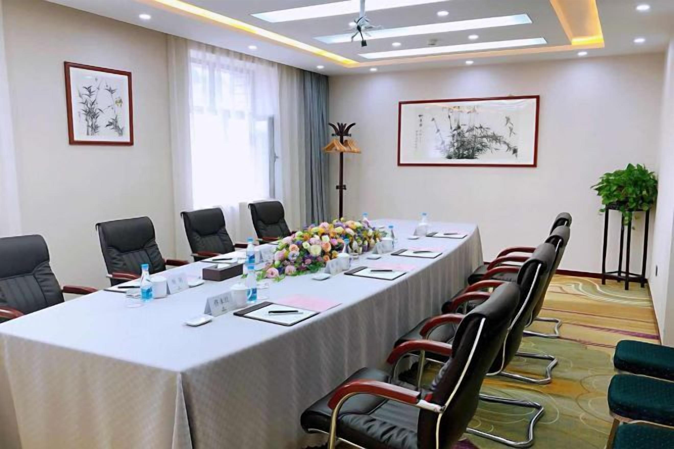 Una sala conferenze con un lungo tavolo, sedie e una pianta.