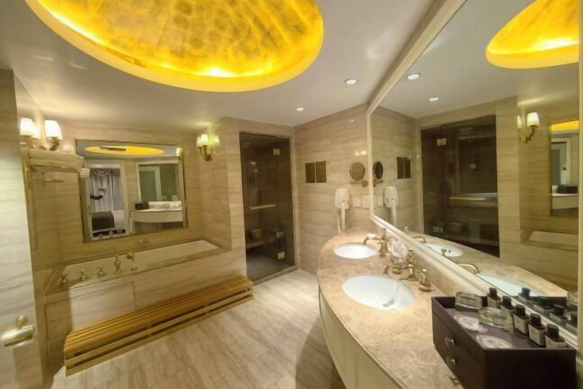 A modern bathroom with a large mirror, two sinks, and a vanity with toiletries.