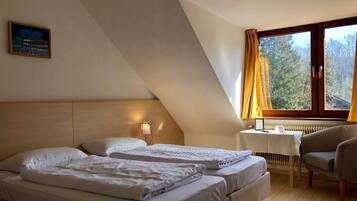 A hotel room with two beds, a desk, a chair, and a window with curtains.