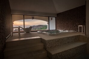 Un baño moderno con una bañera grande, vistas del paisaje y una pared de piedra.