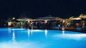 Una piscina con sombrillas y gente alrededor.