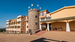 Un hotel con una torre central, varios balcones y un patio empedrado.