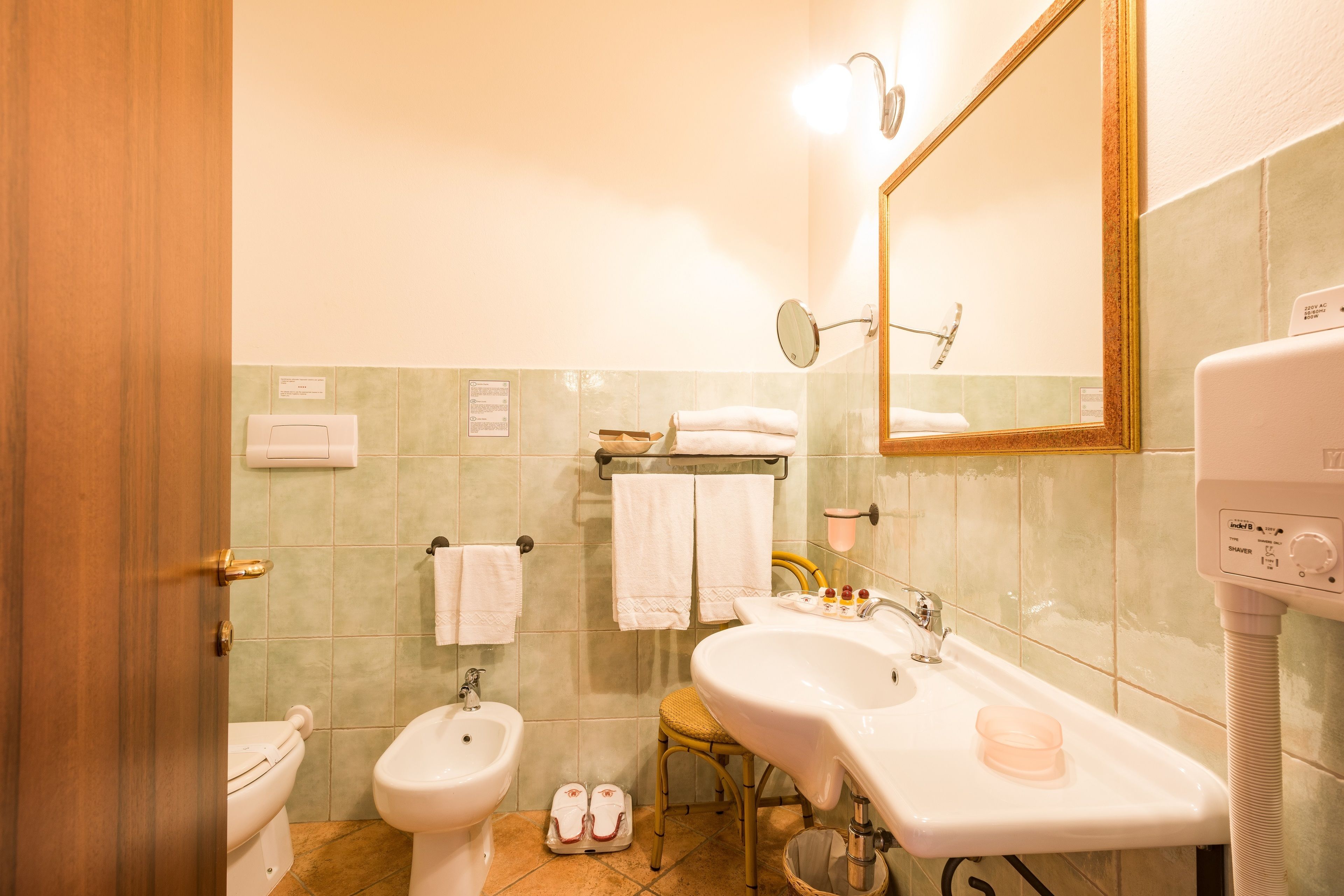 A bathroom with a toilet, bidet, sink, and a mirror.
