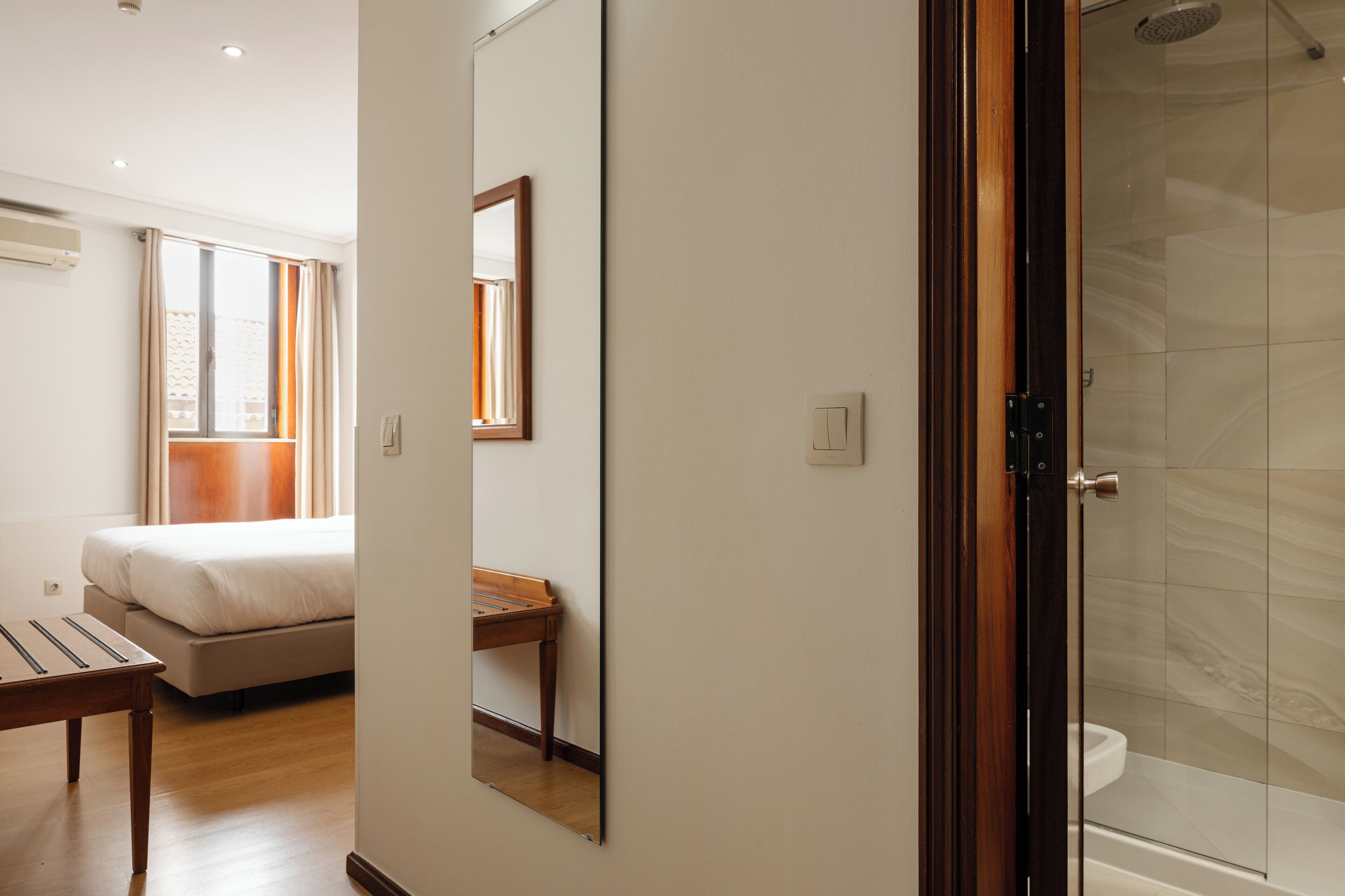 A bedroom with a bed, bedside table, and a window with curtains.