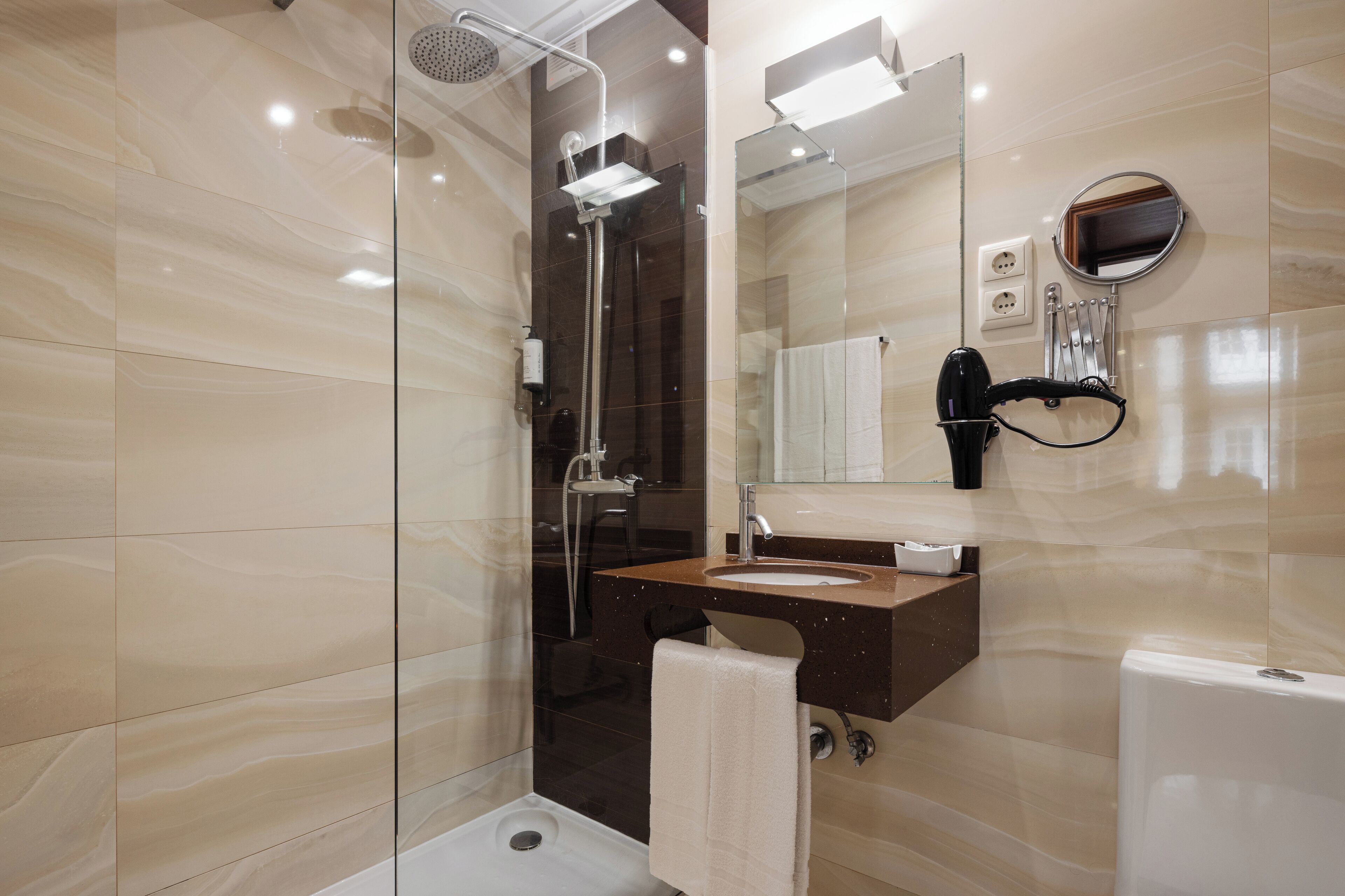 A modern bathroom with a glass-enclosed shower, a vanity with a mirror, and a toilet.