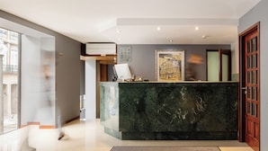 Un espace d’accueil d’hôtel avec un comptoir en marbre, un tableau encadré et un bureau de réception.