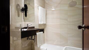 Une salle de bain moderne dotée d’une douche à parois de verre, d’un lavabo intégré et d’une baignoire séparée.