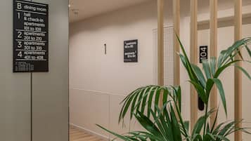 Zona de recepción de hotel con un cartel que indica restaurante, salón y apartamentos con registro.
