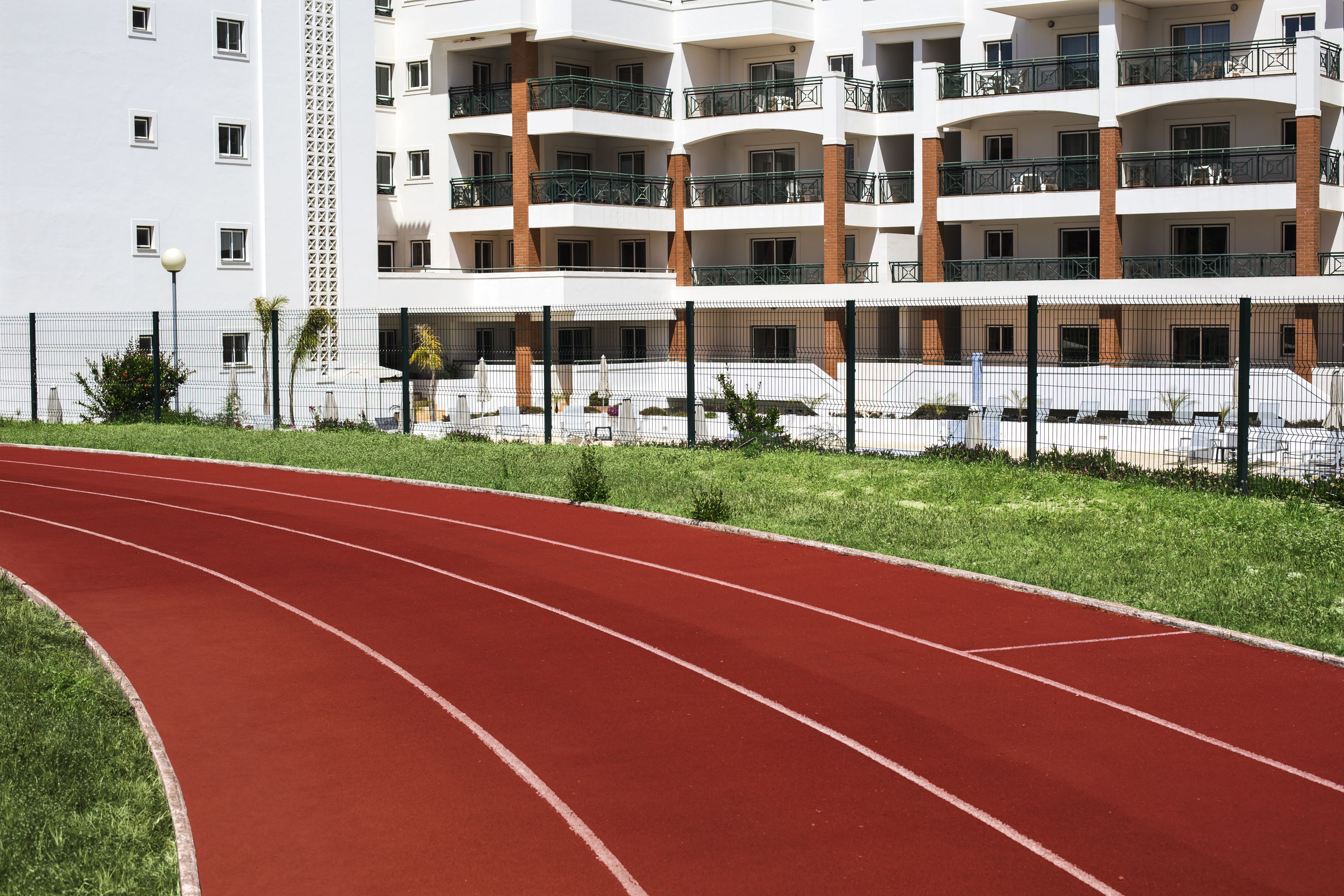 A red running track with a white building in the background.