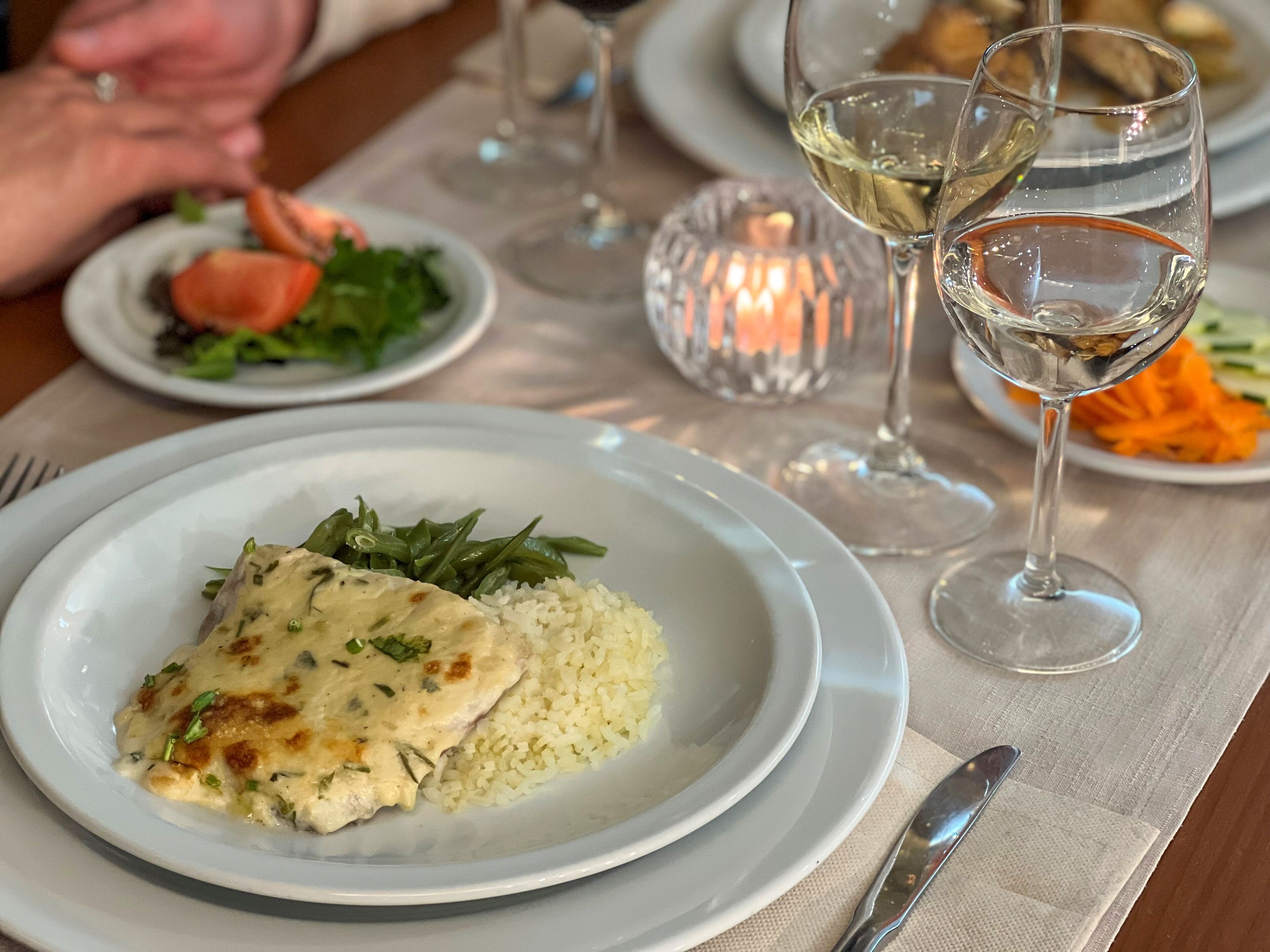 Una mesa de comedor con platos de comida, copas de vino y una vela.