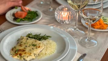 Una mesa de comedor con platos de comida, copas de vino y una vela.