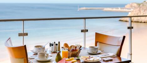 A breakfast table with a view of the beach and ocean.