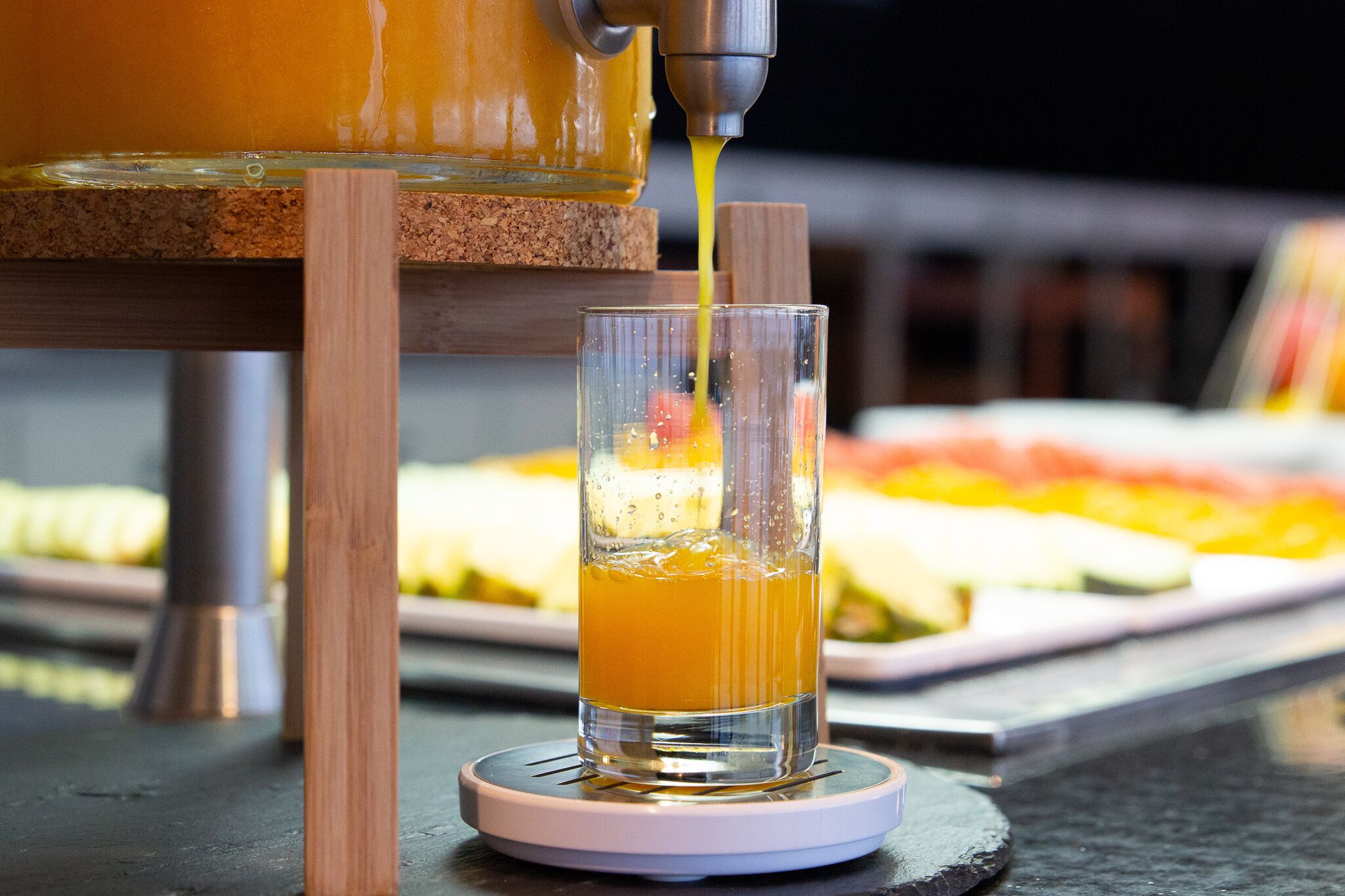Een glas sinaasappelsap dat uit een kraan wordt geschonken.