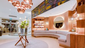A modern interior with a curved sofa, a glass coffee table, and a wooden bookshelf. - Hotel Sol e Mar - Adults Only (Albufeira)
