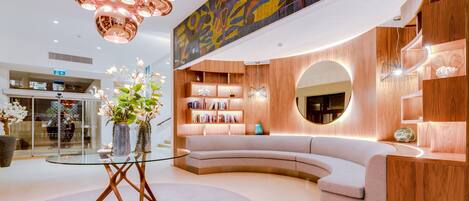 Un intérieur moderne avec un canapé aux lignes courbes, une table basse en verre et une bibliothèque en bois.