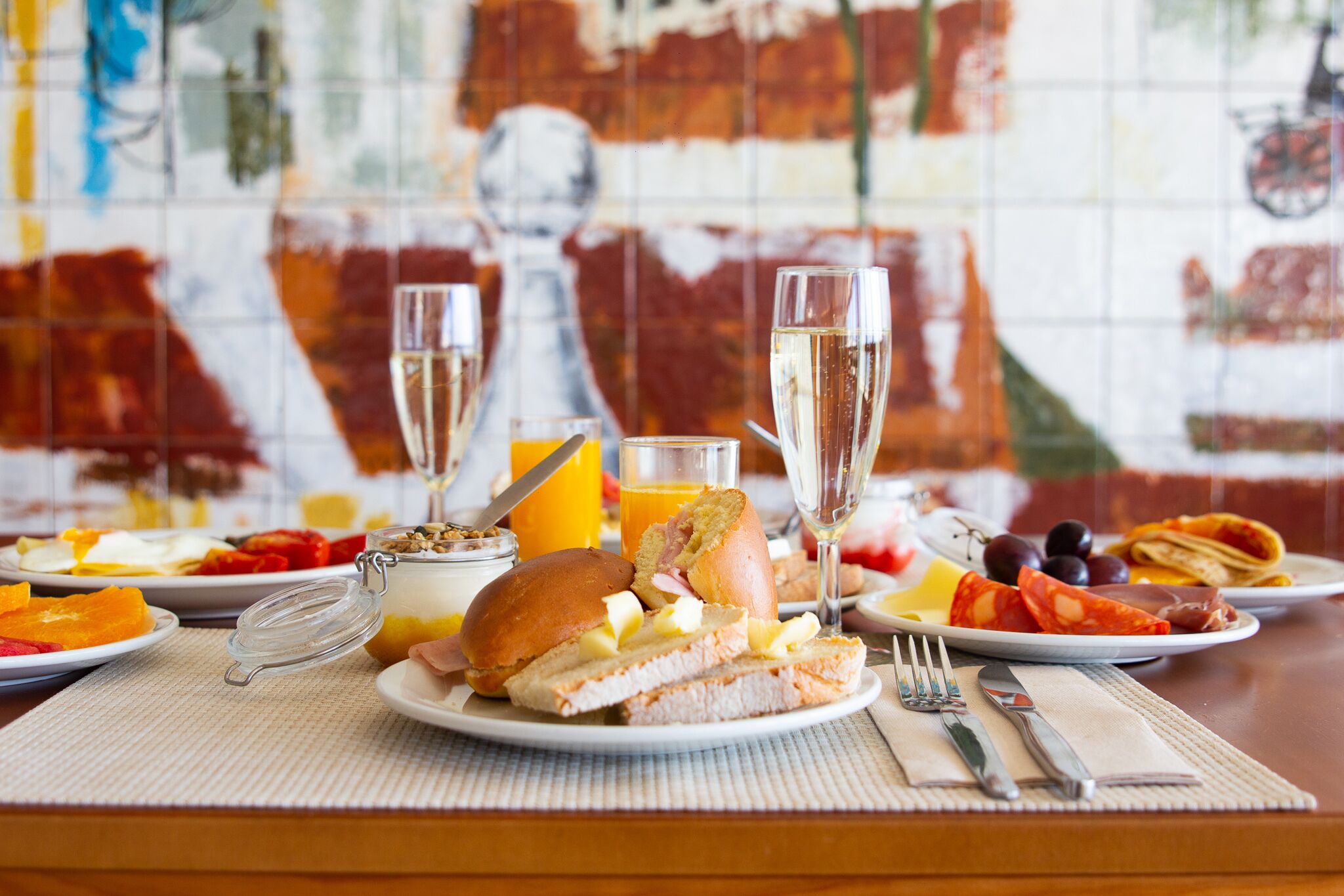 A breakfast setting with a variety of food items, including toast, fruit, and a glass of juice.
