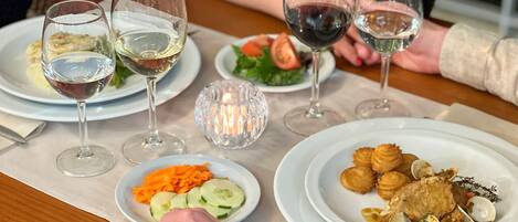 A dining table with plates of food, wine glasses, and a candle.