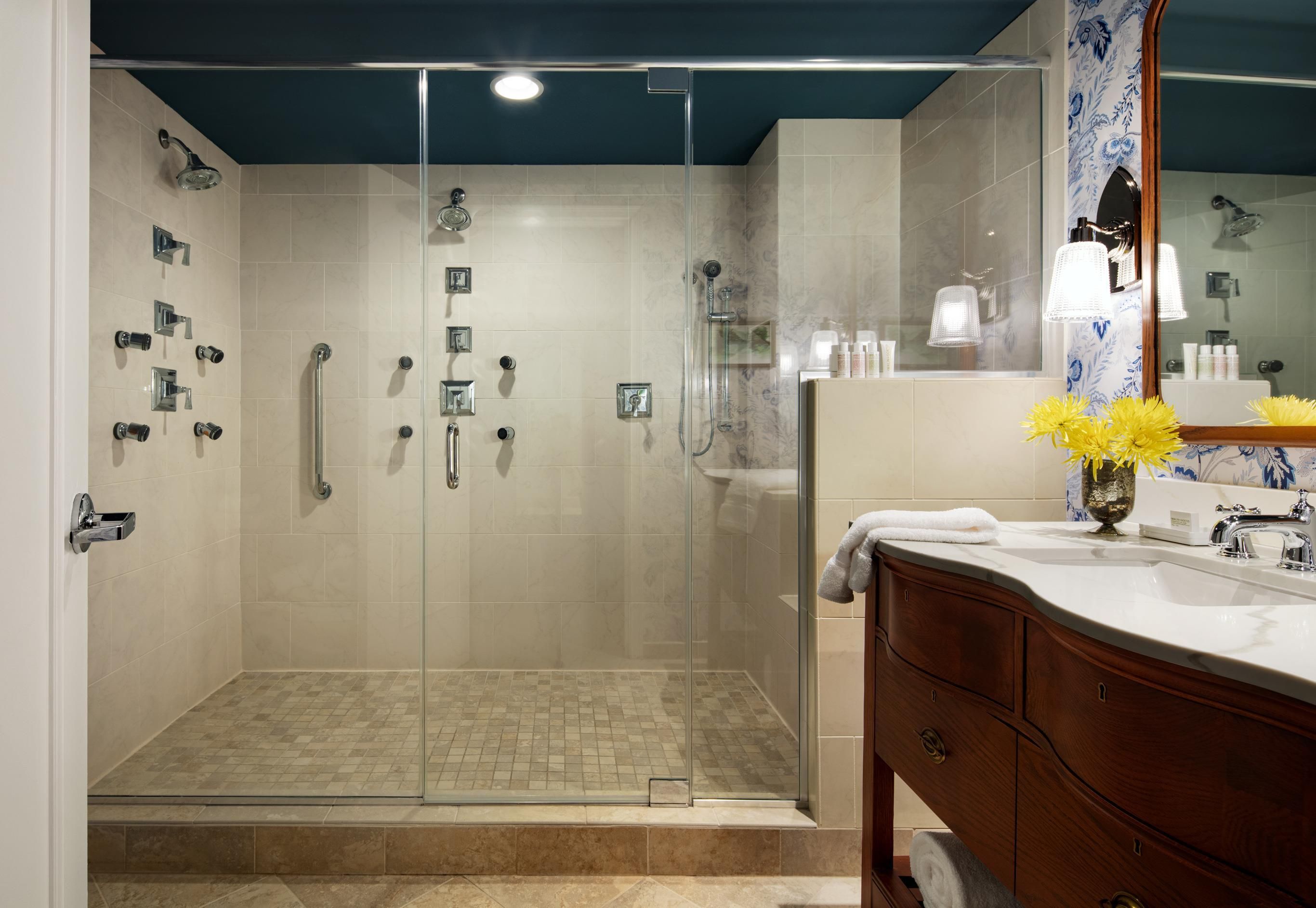 A modern bathroom with a glass-enclosed shower, a vanity with a mirror, and a sink.