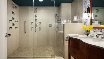 A modern bathroom with a glass-enclosed shower, a vanity with a mirror, and a sink.