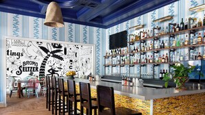 A bar area with a long counter, multiple stools, and a variety of bottles and glasses on shelves.