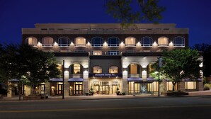 A multi-story building with a prominent entrance, arched windows, and a sign reading "GRADUATE CHAPEL HILL".